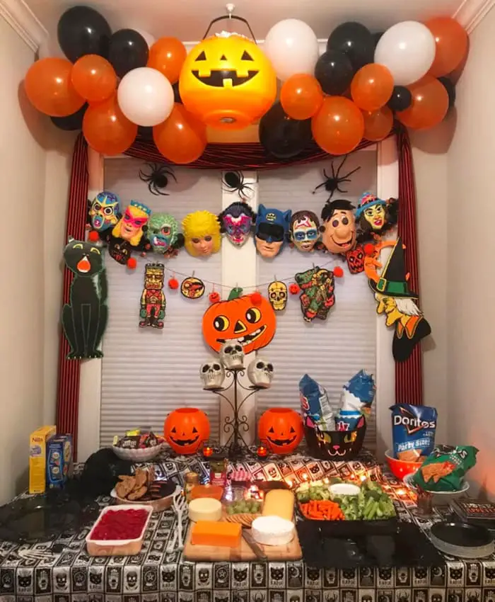 Halloween party food table and decorating ideas - plastic pumpkins, decorations for costume masks, dollar tree Halloween decorations, potluck food and cheap homemade party platters