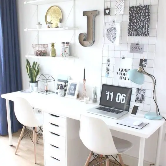 Gorgeous home office idea - love this workspace with the white desk, 2 white office chairs, floating shelves, the navy blue curtains for a pop of color, and all the cute desk items and office supplies!
