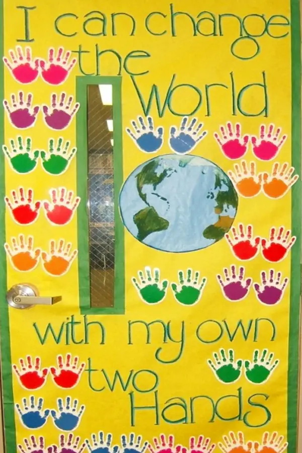 kindergarten classroom door with motivational theme - student handprints with matching bulletin board that says I can change the world with my own two hands